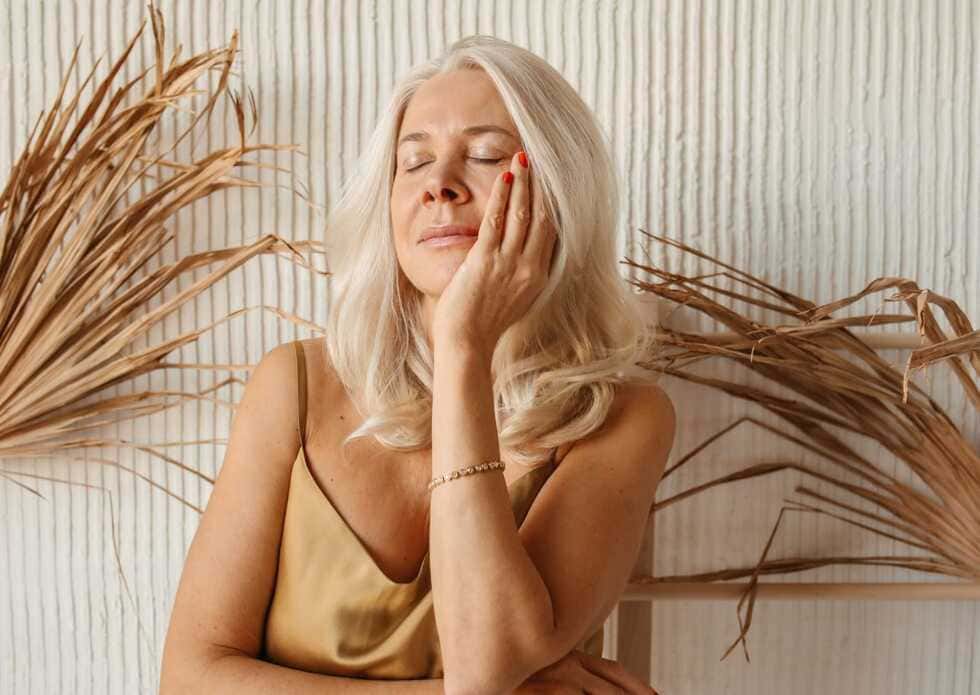 Primer plano de una mujer relajada con piel tersa y saludable tras aplicar un tratamiento facial antiedad.

