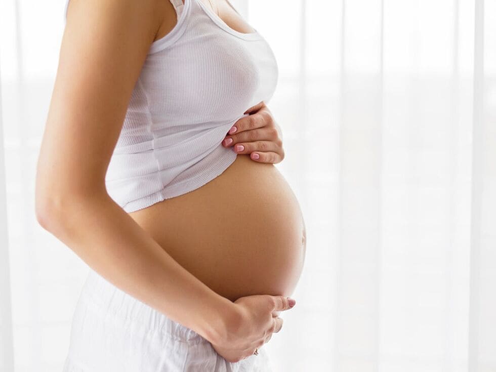 Mujer embaraza sosteniendo su barriga tras un tratamiento de belleza