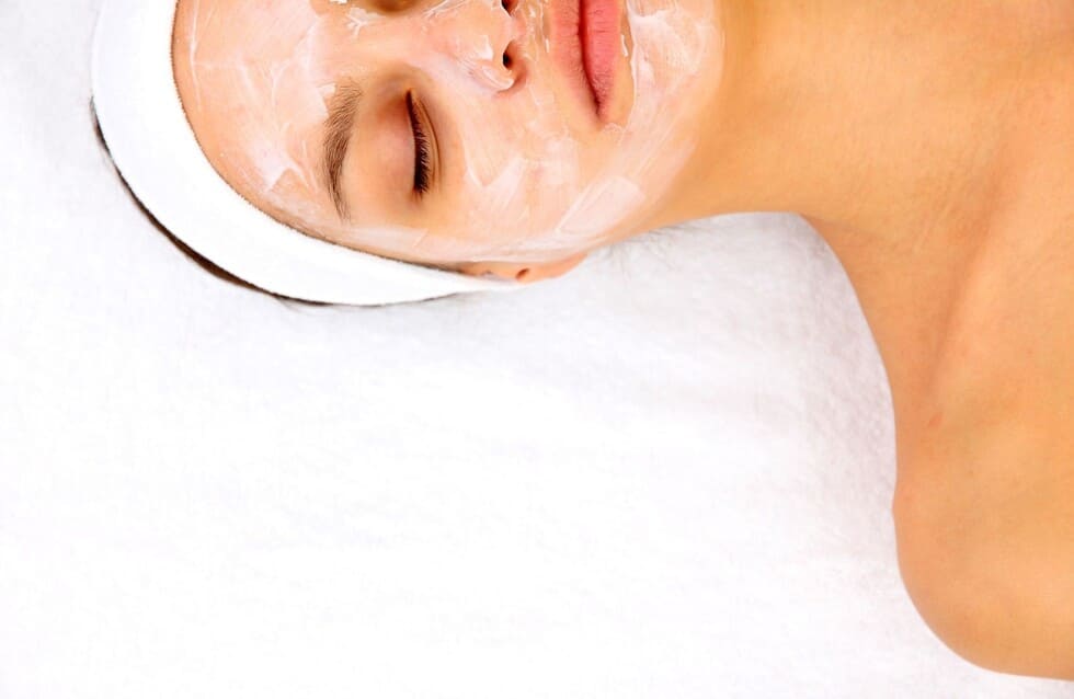 mujer tumbada con crema de limpieza facial en el rostro