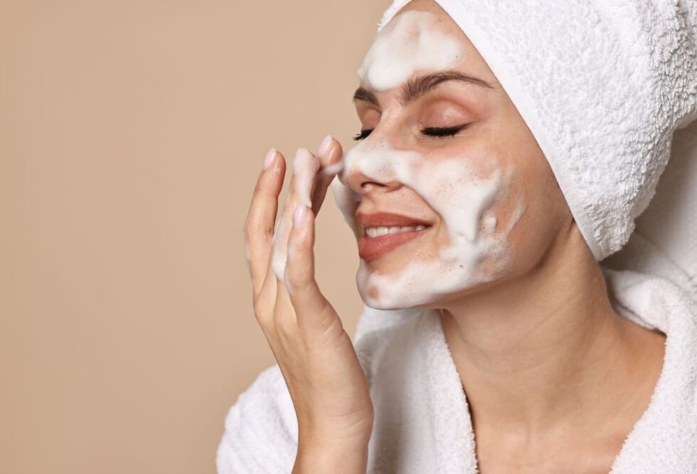 primer plano de una mujer realizándose una limpieza facial y aplicandose productos en el rostro