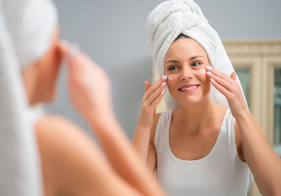 mujer joven aplicandose crema facial par prevenir manchas cutaneas